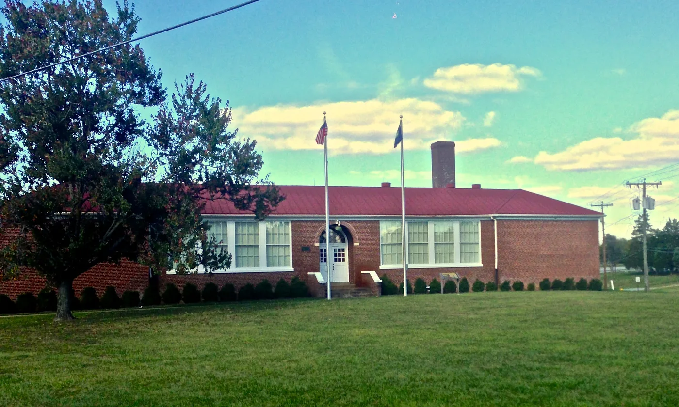 Brick former Robert Russa Moton High School with a red roof, tall windows and two flagpoles in Farmville.