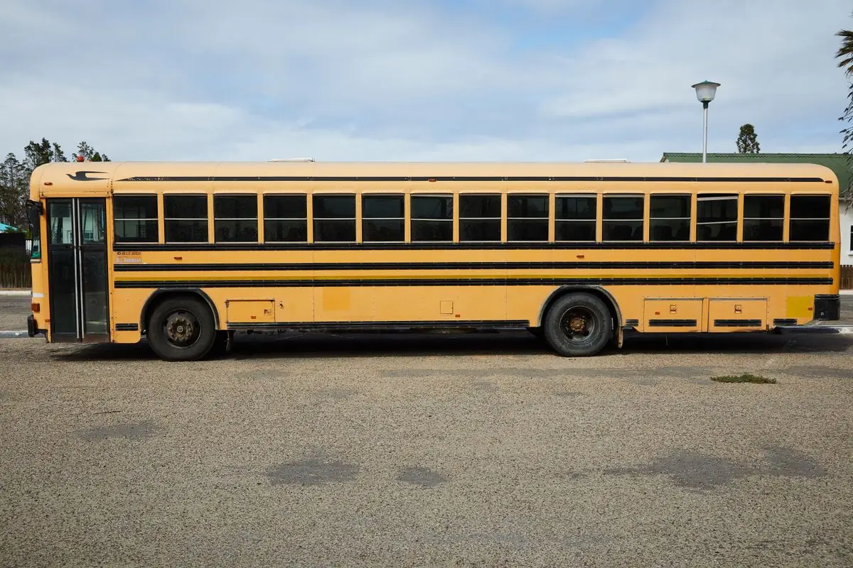 Side view of a yellow school bus parked in an open area.