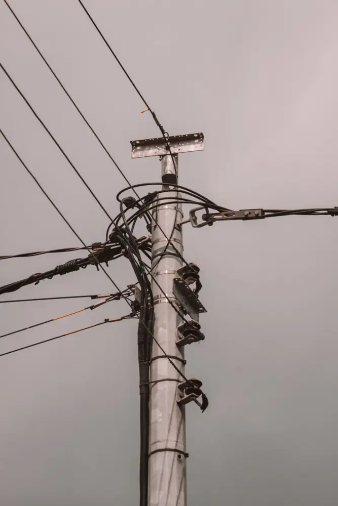 Electric utility pole and power lines under overcast gray sky.
