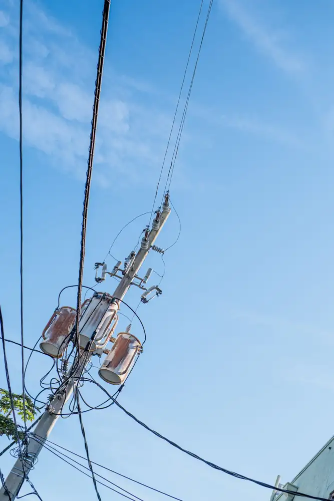 A utility pole with multiple wires against a clear blue sky background.