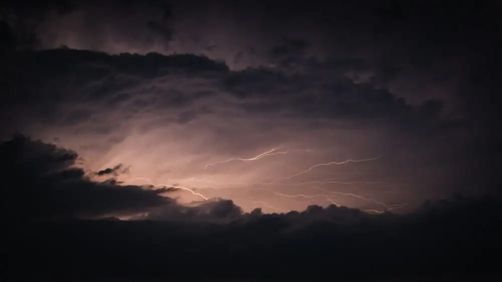 Striking lightning illuminating dark storm clouds in a dramatic night sky