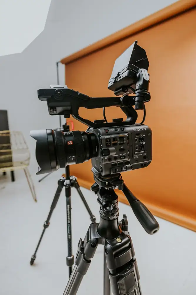 High-quality cine camera setup in a modern studio environment with orange backdrop.