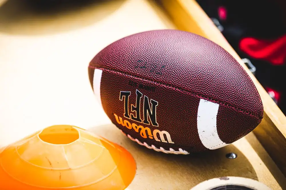 American football on a training bench beside an orange cone