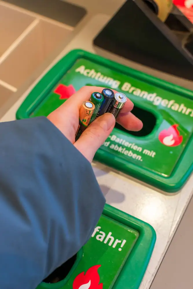 Hand placing used batteries into recycling bin in Berlin, Germany.