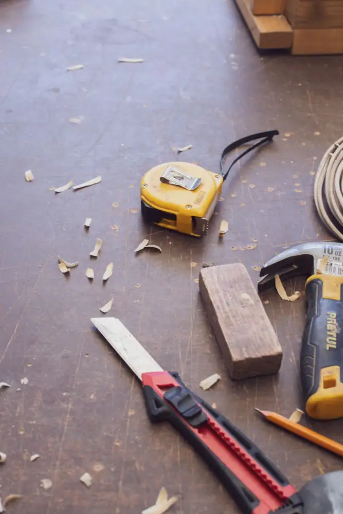 Close-up of various woodworking tools scattered on a wooden workshop surface.