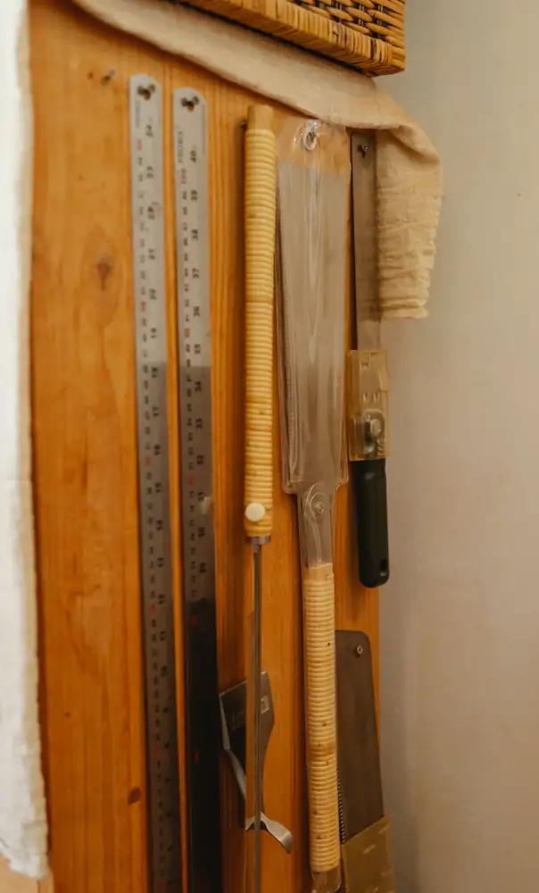 Set of various instruments for carpentry including rulers hanging with saws on wooden wall in joinery workshop