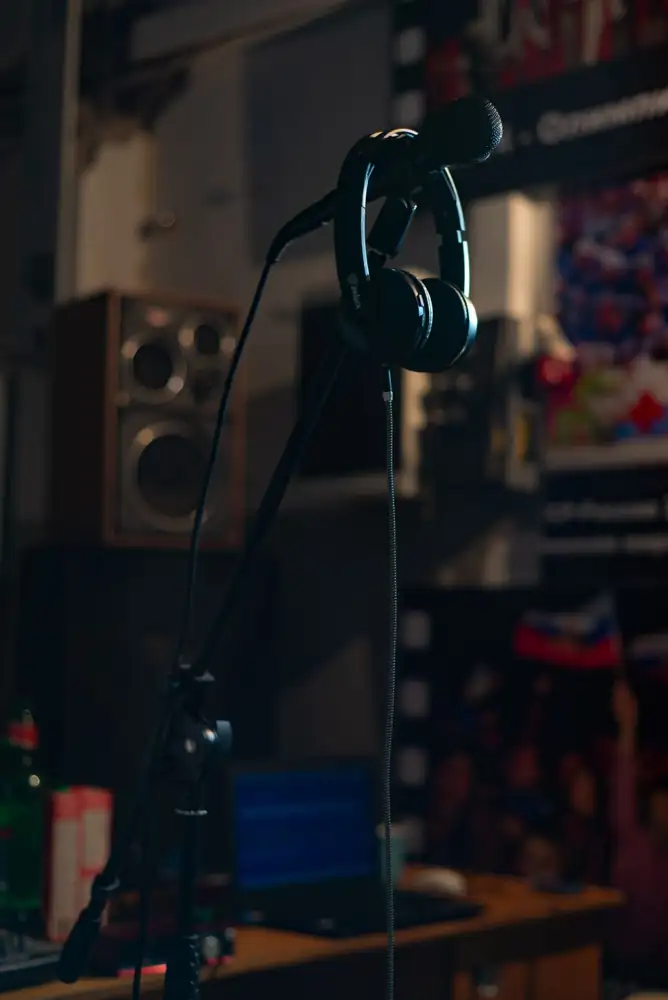 Close-up of a microphone stand and headphones in a dimly lit music studio.