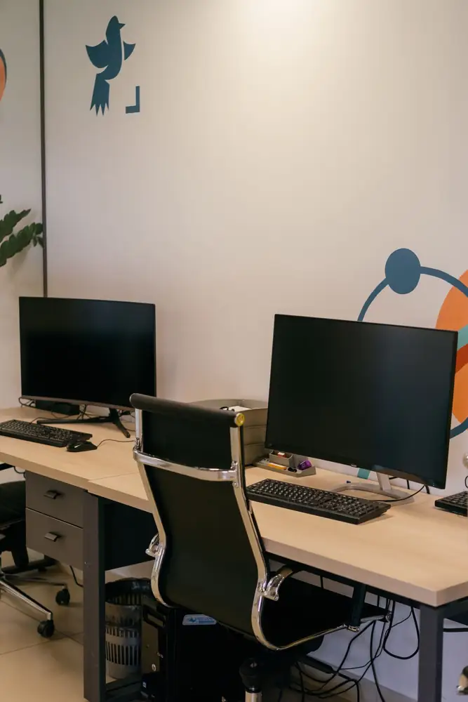 Empty modern office space with two desks, monitors and chairs.