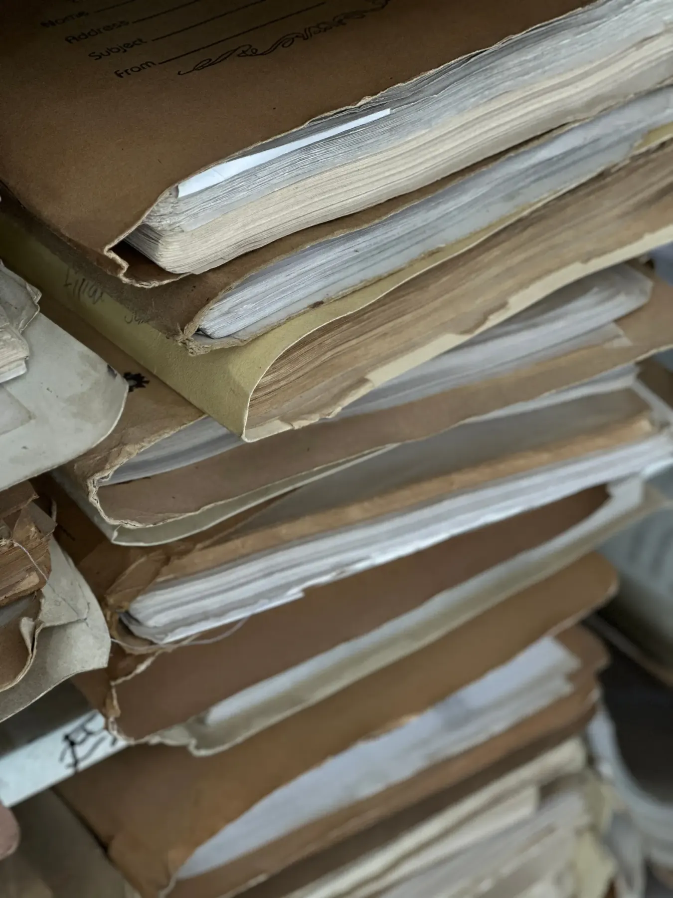 Stack of aged paper files in brown archive folders
