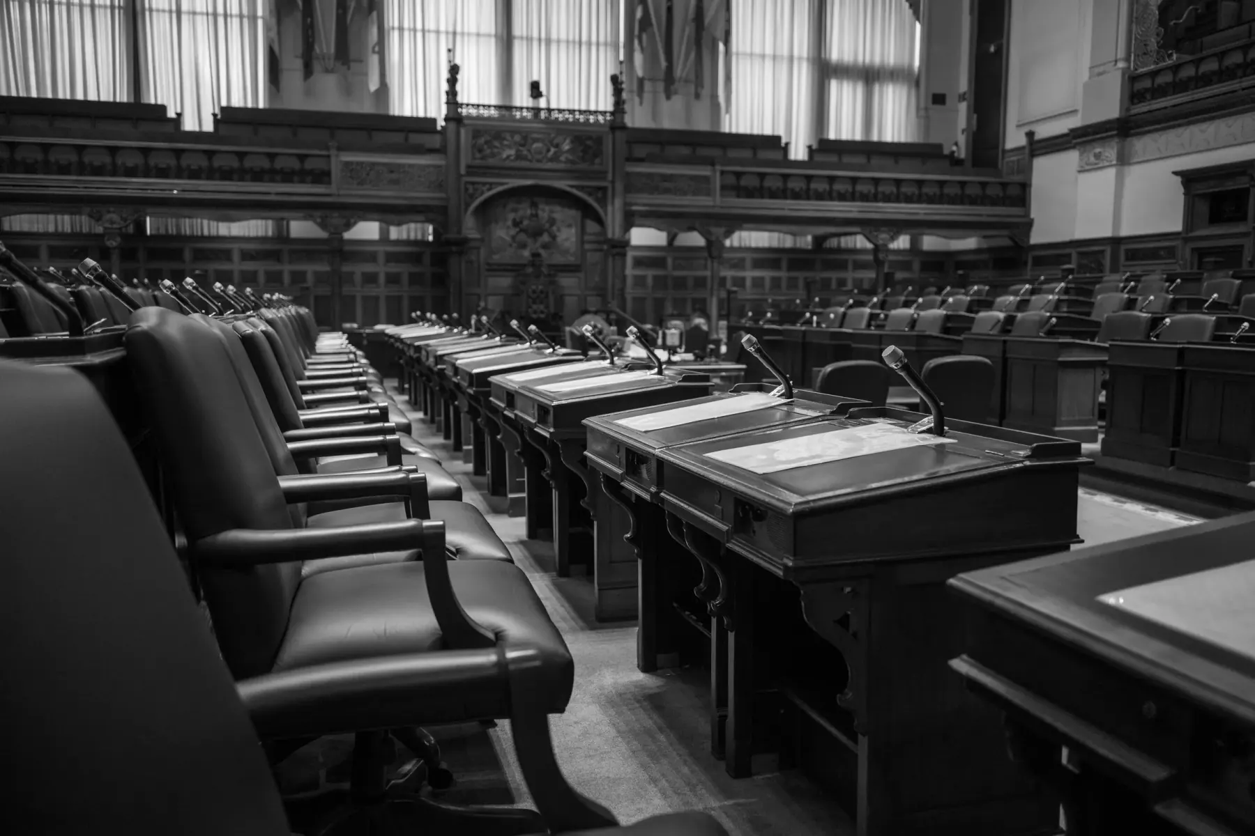 Black-and-white view of an empty legislative chamber with desks